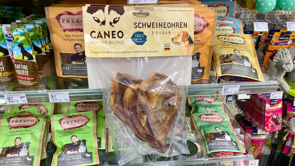 In einem Regal hängt neben anderen Produkten eine Packung getestete Schweineohren für Hunde.
