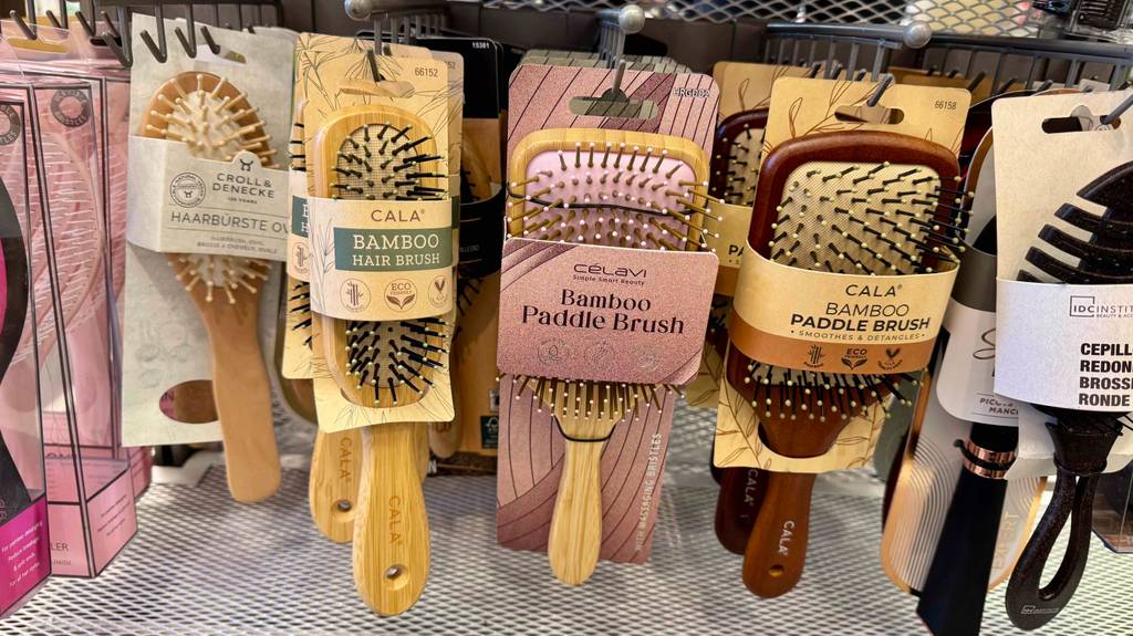 Getestete Paddelbürste hängt in einem Regal neben anderen Bürsten.