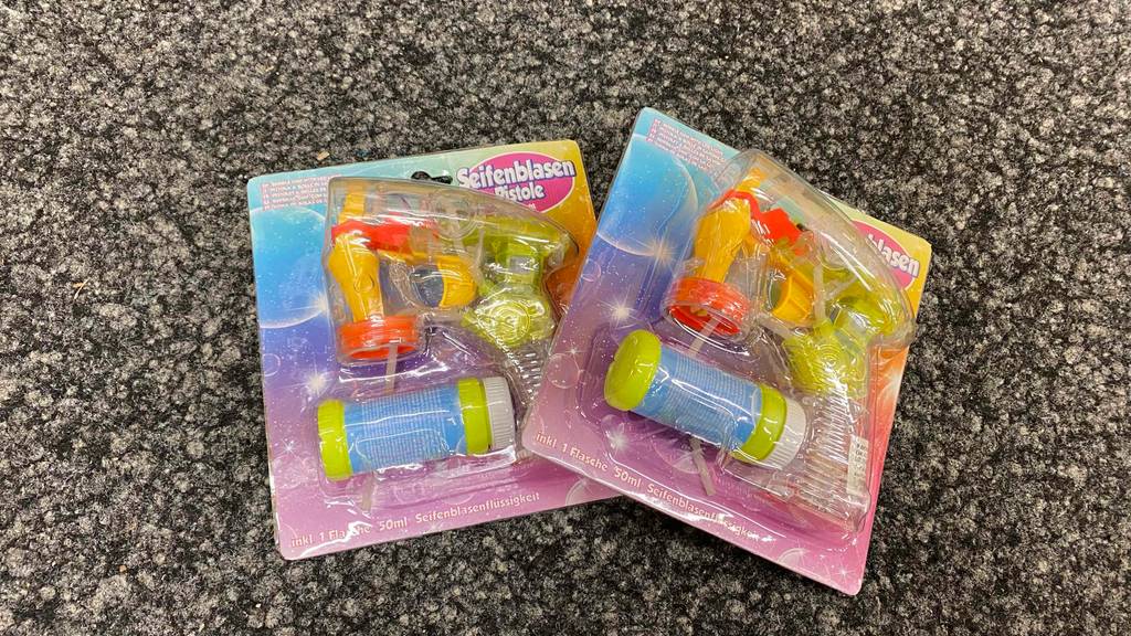Im Test: Zwei Packungen der Seifenblasenpistole liegen leicht übereinander auf einem grauen Boden.