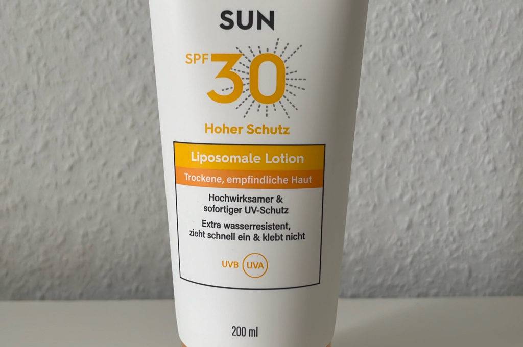 Eine getestete Tube Daylong-Sonnencreme steht vor einer hellen Wand auf einer weißen Fläche.