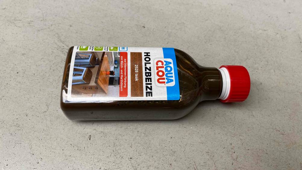 Holzbeize getestet: Eine Flasche liegt horizontal auf einer Steinfläche
