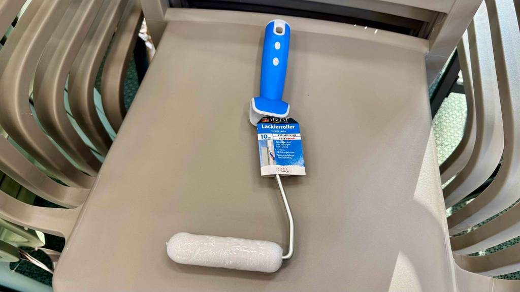 Lackierwalzen-Test: Der Lackierroller mit der 5-cm-Walze liegt auf mehreren gestapelten Kunststoffstühlen.