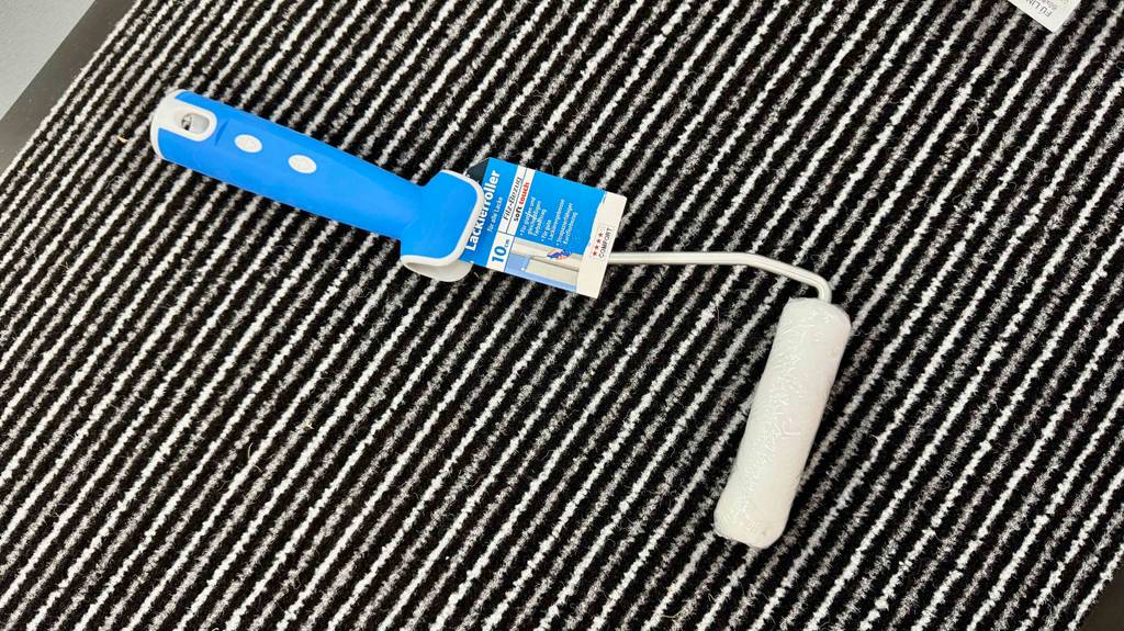 Lackierwalzen im Test: Der Lackierroller mit der 5-cm-Walze liegt auf einem gestreiften Fußabstreifer.