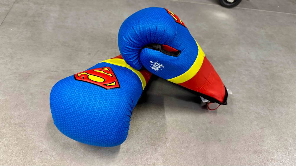 Ein Paar getestete Kinder-Boxhandschuhe sind auf einem Boden platziert.