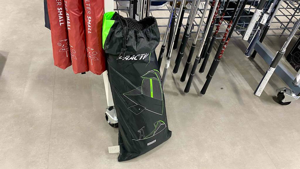 Golf-Übungsnetz-Test: Die Tasche eines Golf-Übungsnetzes mit geöffneter Zugschnur ist in einem Geschäft an einem Regalangelehnt.