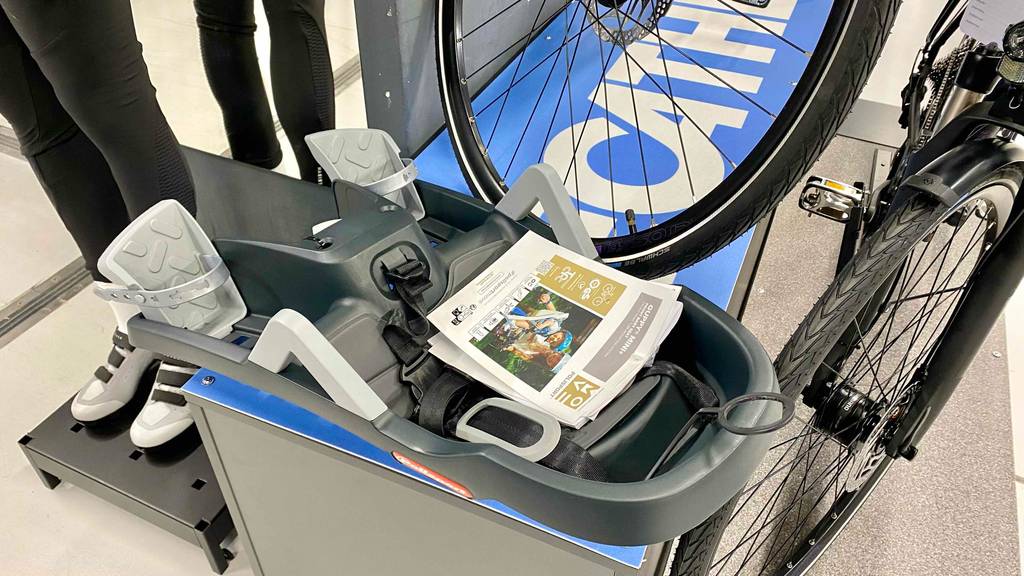 Kindersitz-Fahrrad-vorne im Test: ein Kindersitz ist auf einem Regal gestellt neben einem Fahrrad.