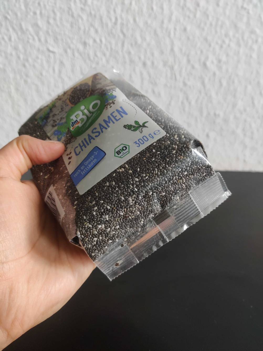 Chia-Samen getestet: Eine Hand hält die Unterseite einer Packung vor eine helle Wand.