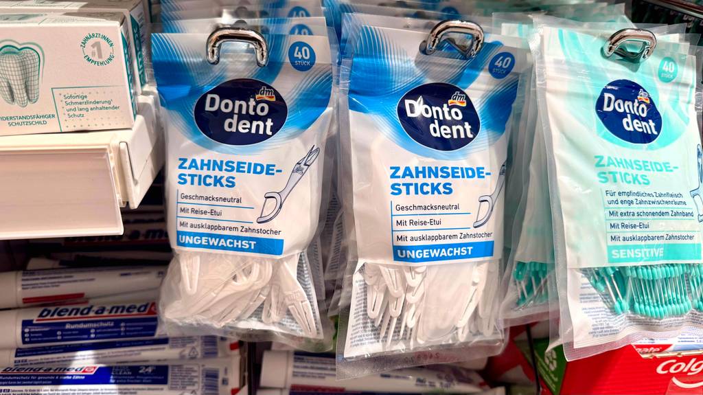 Test: Mehrere Packungen Zahnseide-Sticks hängen in einem Regal in verschiedenen Ausführungen.