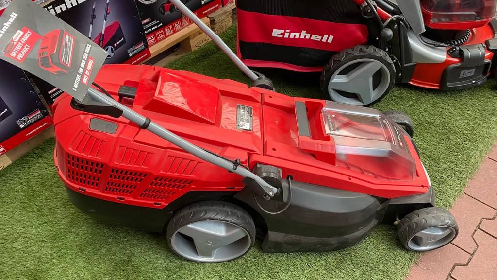 Einhell-Rasenmäher getestet: roter Einhell-Rasenmäher von der Seite auf einem Kunstrasen stehend.