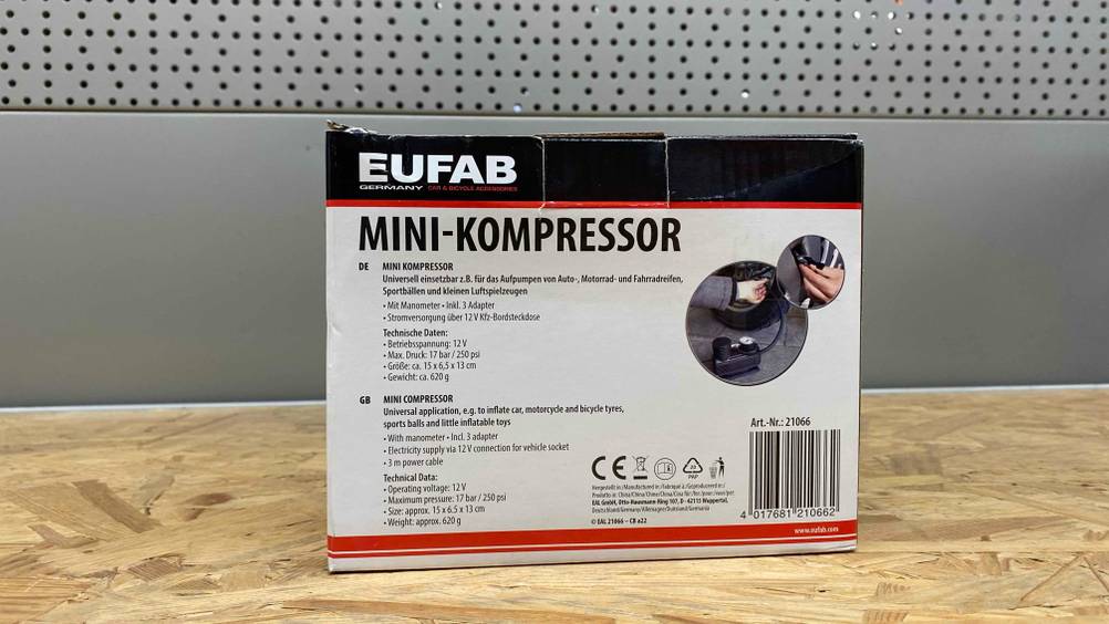 Im Test: Die Rückseite eines verpackten 12V-Kompressors vor einer grauen Fläche.
