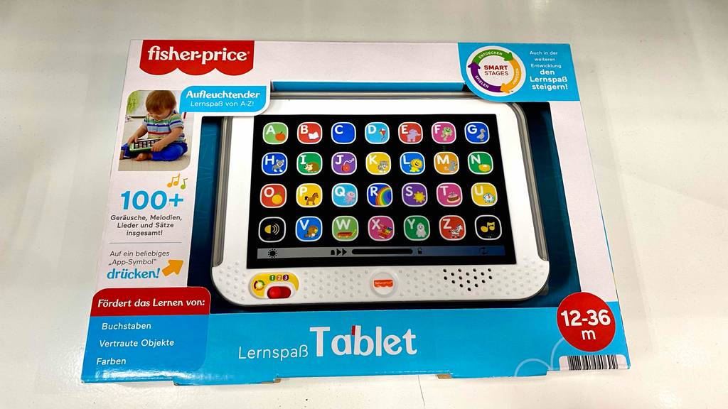 Kinder-Tablet getestet: Kinder-Tablet in Verpackung mit 100+ Geräuschen, Melodien, Lieder und Sätzen, mit Altersangabe von 12 bis 36 Monaten liegt auf einem Boden.