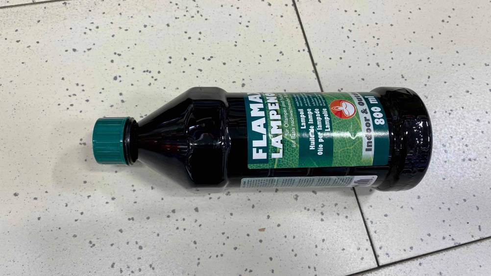 Lampenöl im Test: eine getönte Flasche Lampenöl auf horizontal auf einem Boden liegend.