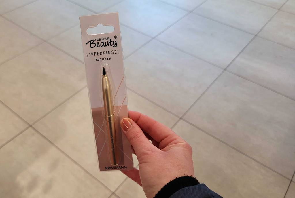 Der getestete Lippenpinsel wird in der Hand gehalten.