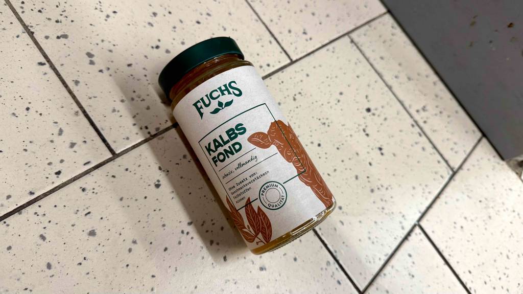Ein getestetes Glas Kalbsfond liegt auf einem Boden.