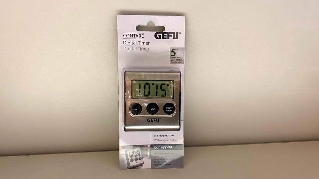 Ein getesteter Digitaler-Kurzzeitwecker ist in der Verpackung an eine Wand angelehnt.