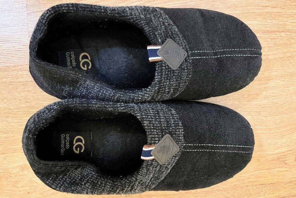 Hausschuhe Herren im Test: Schuhe von oben auf Holzoberfläche
