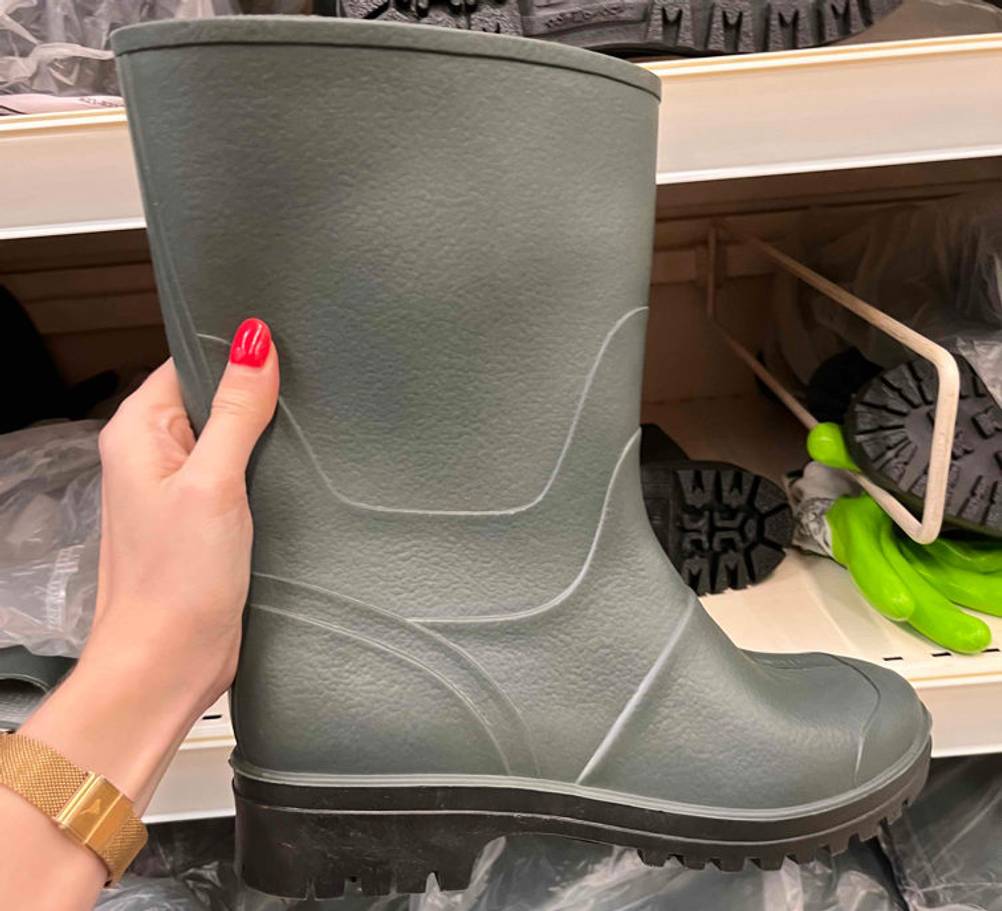 Gummistiefel-Herren im Test: grauer Gummistiefel wird in der Hand vor einem Regal gehalten.