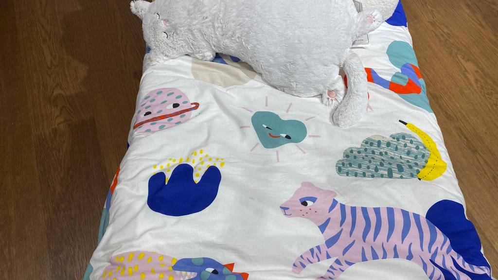 Kinderbettwäsche im Test: Kinderbettwäsche zusammengefaltet auf einem Boden mit einem Kuscheltier darauf.