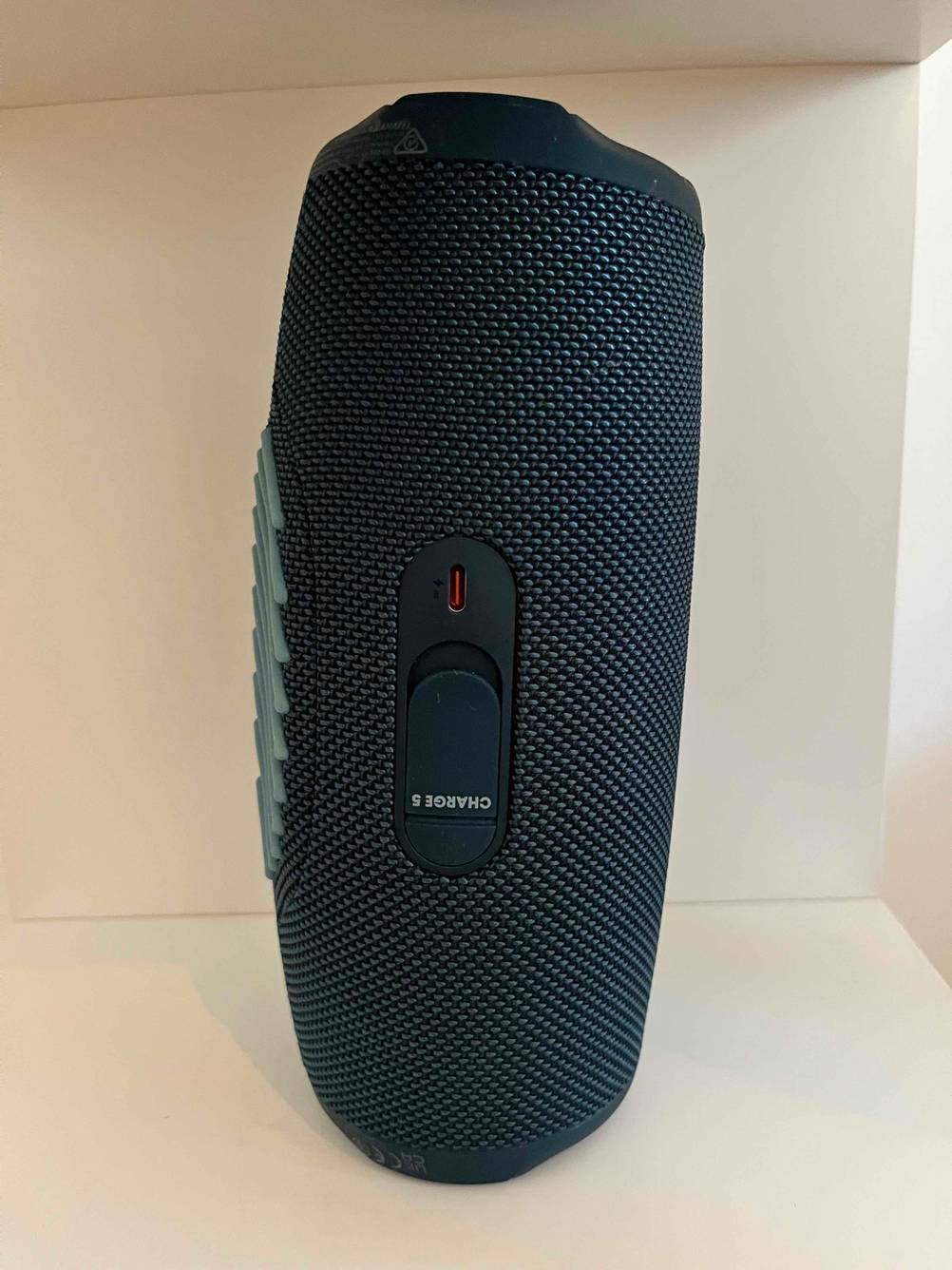 Bluetooth-Lautsprecher im Test: Ein Bluetooth-Lautsprecher steht auf seiner kurzen Seite in einem hellen Regal, Bedienelemente nach vorne