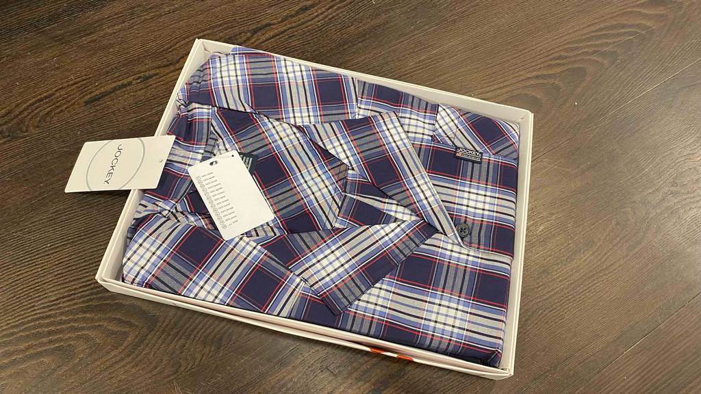 Im Test: In einem geöffnetem Karton liegt ein Pyjama für Herren auf einem Holzboden.