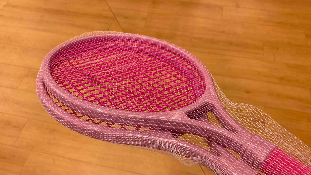 Tennisschläger-Kinder getestet: Zwei rosafarbige Tennisschläger in einem Netz vor einem Boden.