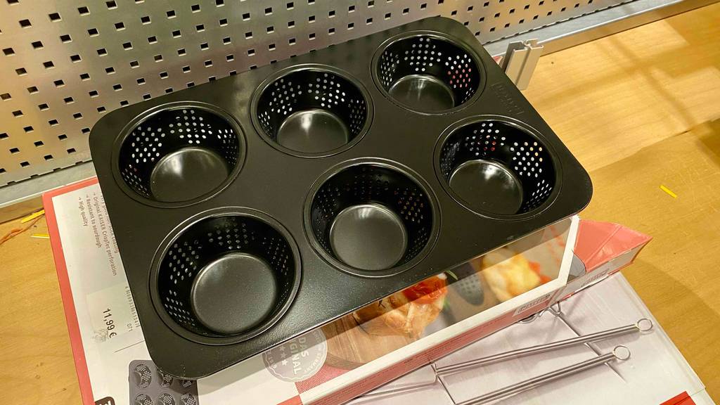 Auf einem farbigen Untergrund steht eine Brötchen-Backform.