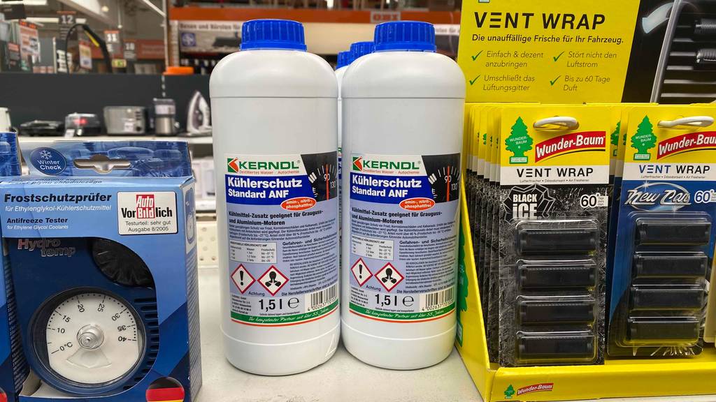 Im Test: Mehrere Flaschen Kühlerfrostschutz stehen in einem Regal neben anderen Produkten
