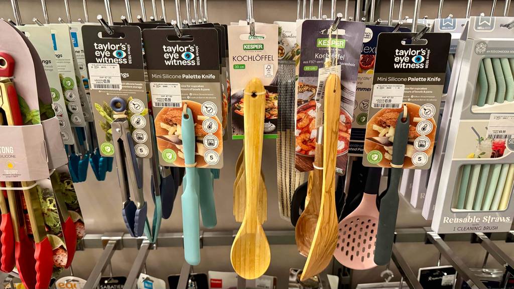 Mehrere getestete Holz-Kochlöffel hängen in einem Regal neben anderen Artikel.
