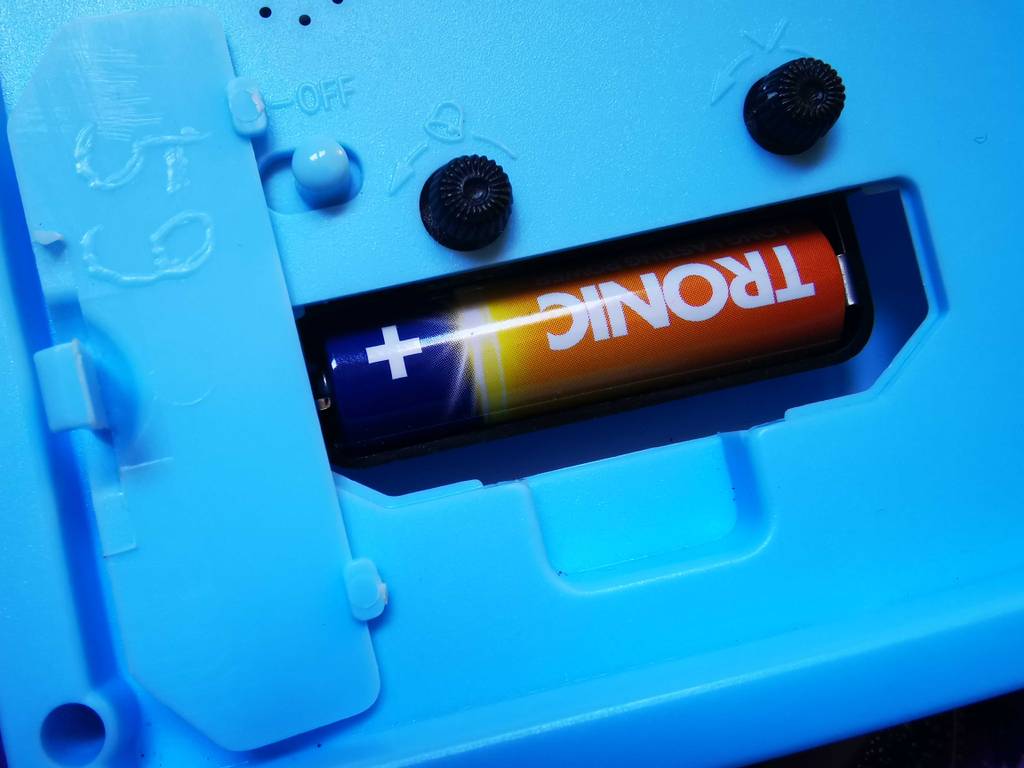 Im Test: Der Kinderwecker ohne Ticken von hinten betrachtet, der Fokus liegt auf dem Batteriefach inklusive Batterie.