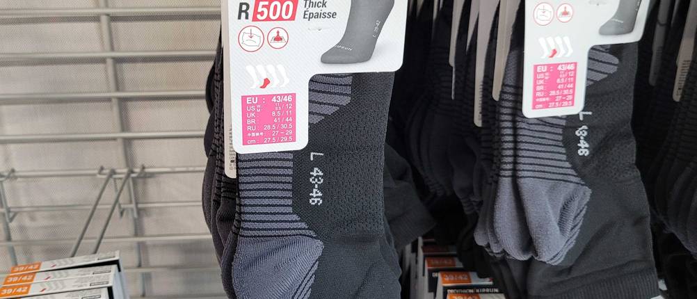 Frontansicht der getesteten Laufsocken, die in einem Regal hängen.