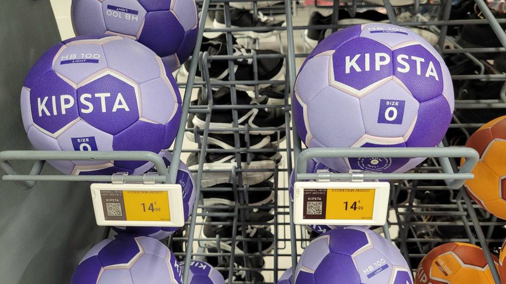 Ein getesteter Handball Größe 0 von Kipsta liegt auf einem Regal mit weiteren Bällen.