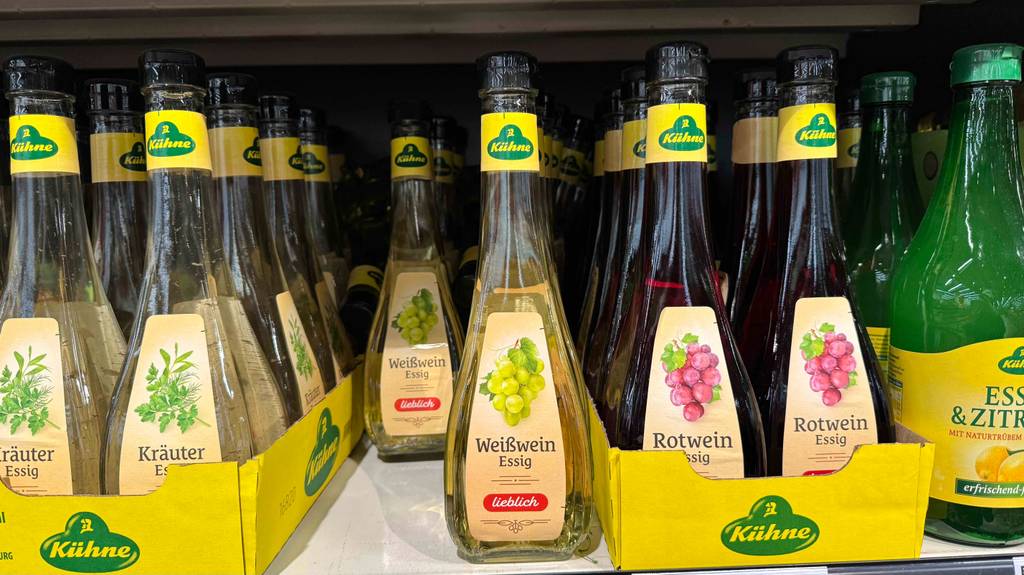 Weißweinessig getestet: Mehrere Flaschen des Essigs befinden sich in einem Regal neben anderen Essigsorten.