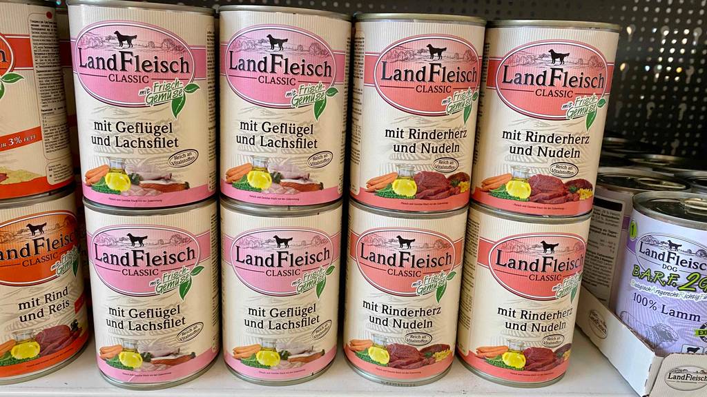 Mehrere getestete LandFleisch-Hundefutter-Dosen stehen im Regalfach nebeneinander