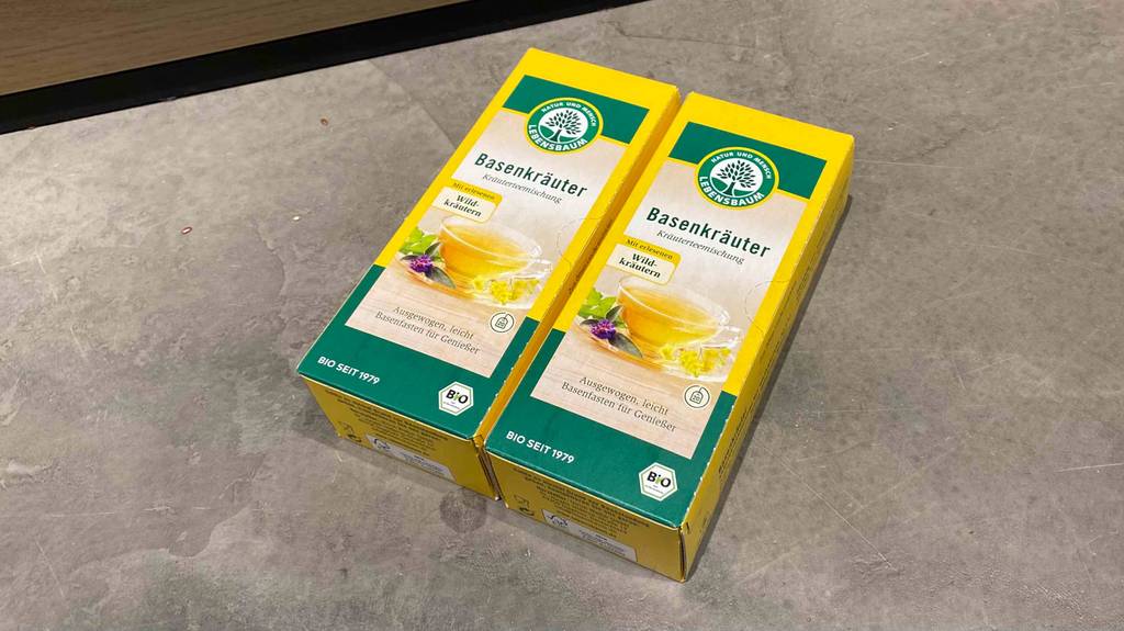 Im Test: Auf einem Betonboden liegen zwei Packungen Basentee nebeneinander.