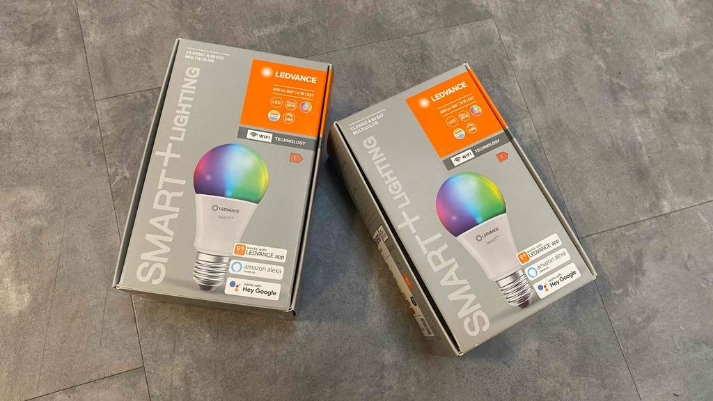 Im Test: Zwei verpackte Smarte Glühbirnen liegen nebeneinander auf einer grauen Fläche.