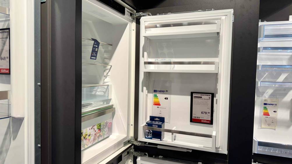 Der geöffnete Einbaukühlschrank mit 88 cm im geöffneten Zustand, worin sich das Preisschild befindet.