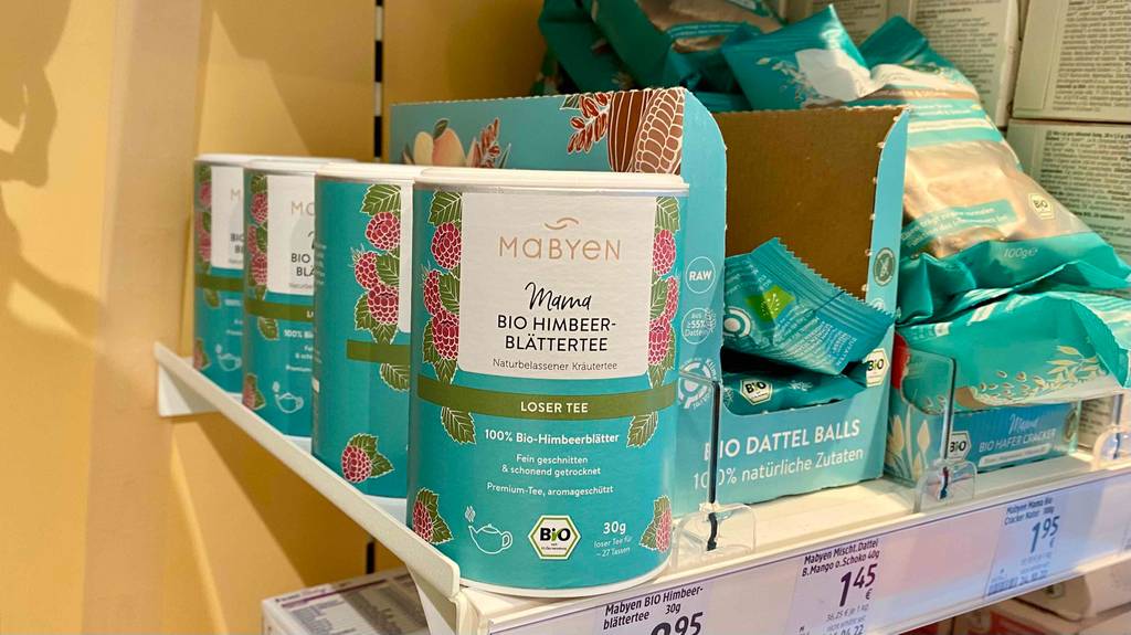 Im Test: Mehrere Dosen Himbeerblättertee im Regal neben anderen Produkten.