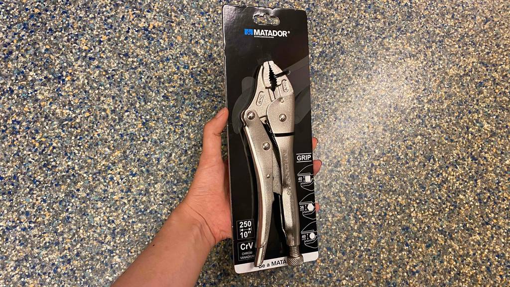 Die getestete Gripzange in ihrer Originalverpackung wird von einer Hand vor eine bunten Unterlage gehalten
