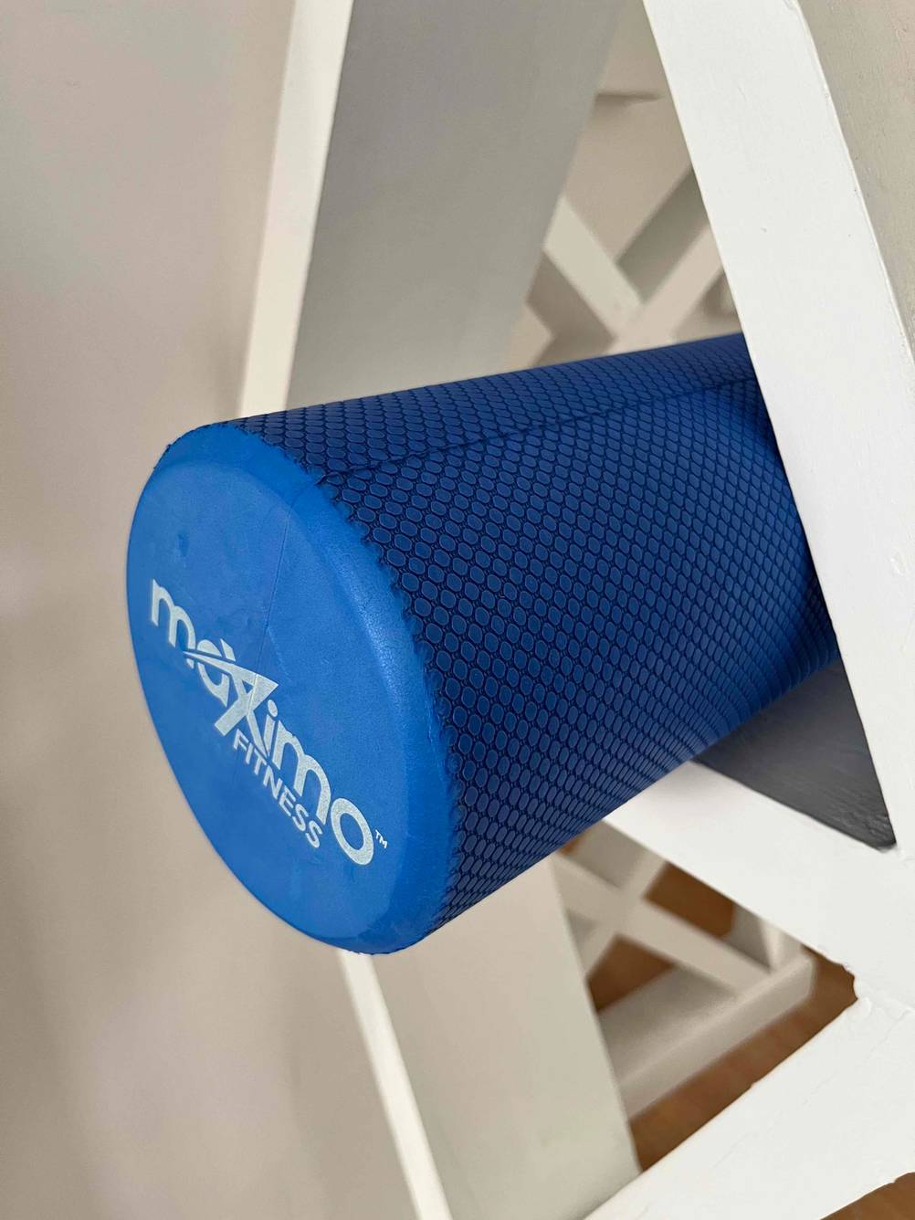 Massageroller im Test: ein blauer Massageroller mit dem Ende aus einem Regal herausschauend.