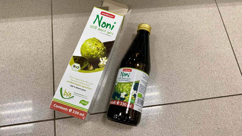 Ein getesteter Noni-Saft liegt neben der Verpackung auf dem Boden.