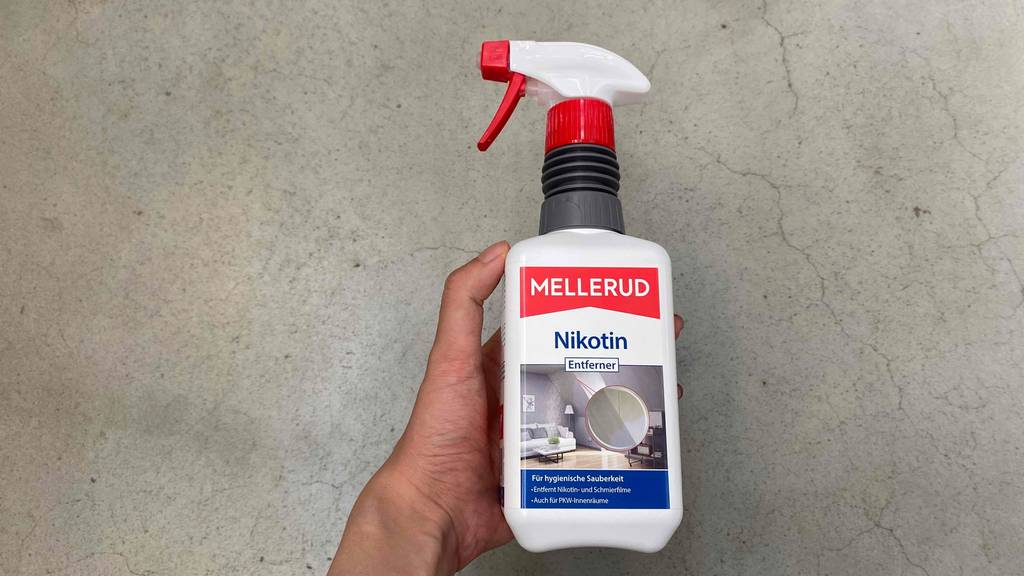 Hand hält von vorn 500-ml-Sprühflasche mit Mellerud-Nikotinentferner im Test.