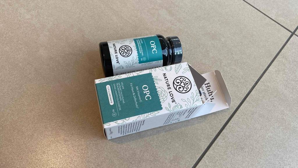 OPC getestet: Verpackung und Döschen von OPC-Präparat liegen auf einem Boden.