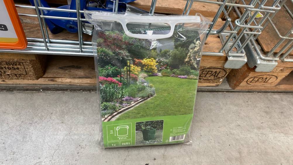 Im Test: Ein Gartenabfallsack in seiner Verpackung lehnt an einem Gitter.