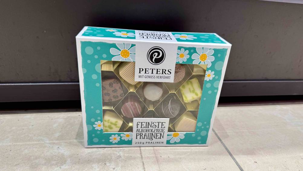 Eine Packung der getesteten Peters-Pralinen stehen auf einem Boden.