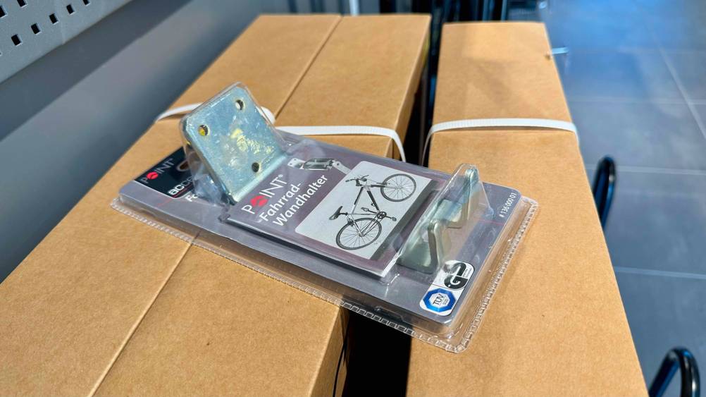 Die getestete Fahrrad-Wandhalterung, die sich in der Verpackung befindet liegt auf einem Karton.