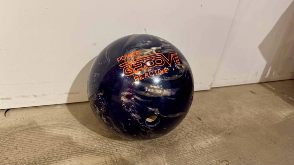 Die dunkelblaue getestete Bowlingkugel liegt auf einem Holzboden.