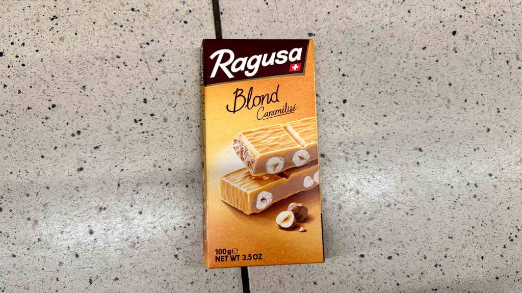 Eine Tafel getestete schweizer Schokolade mit 100 g Inhalt der Marke Ragusa von vorne ersichtlich.