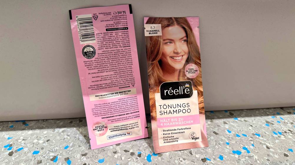 Zwei Packungen des getesteten Tönungsshampoos, wobei eine Packung von der Rückseite ersichtlich ist und die andere von der Vorderseite.