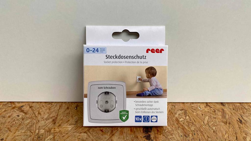 Steckdosensicherung im Test: Steckdosensicherung von Reer mit dem Hinweis 0-14 Monate steht vor einer weißen Wand.