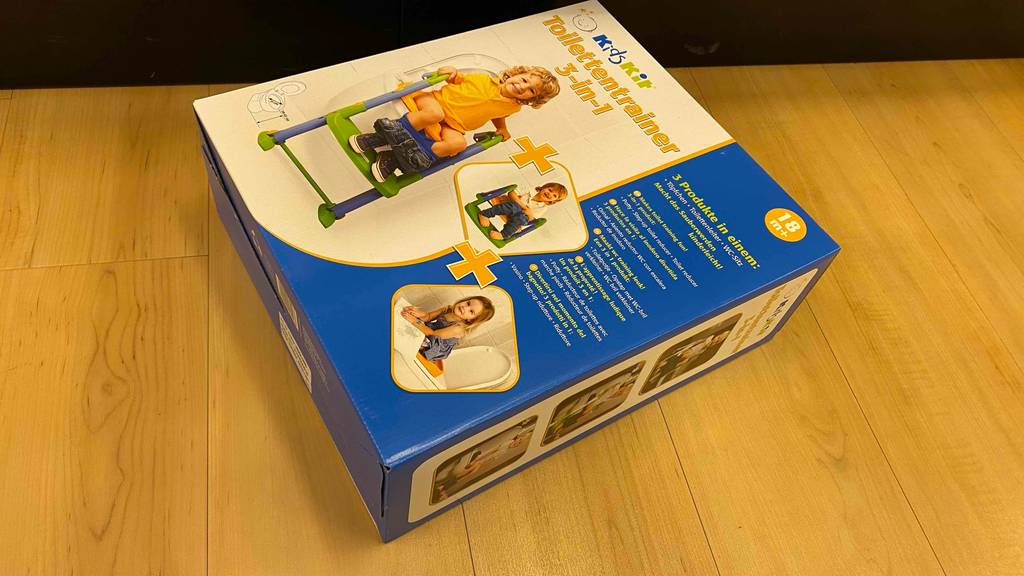Im Test: Auf einem Holzboden liegt ein verpackter Toilettentrainer.